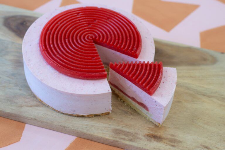 Een vegan aardbeienmoussetaart van Trashure Taarten, de bakker in Nijmegen, met een gesneden punt.