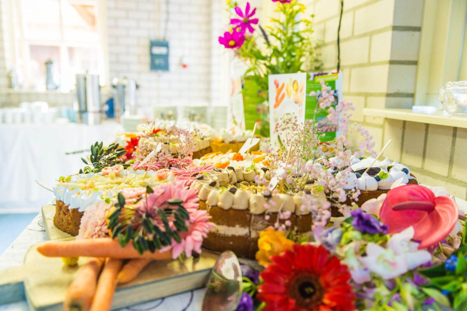 Een sierlijk gevulde tafel met taarten, bloemen en wortels.