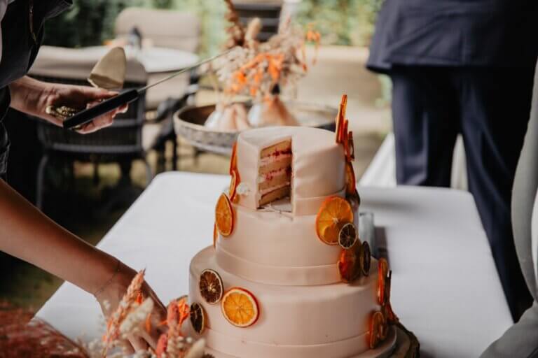Een vegan bruidstaart van Trashure Taarten, de vegan bakker in Nijmegen, wordt gesneden op een bruiloft.
