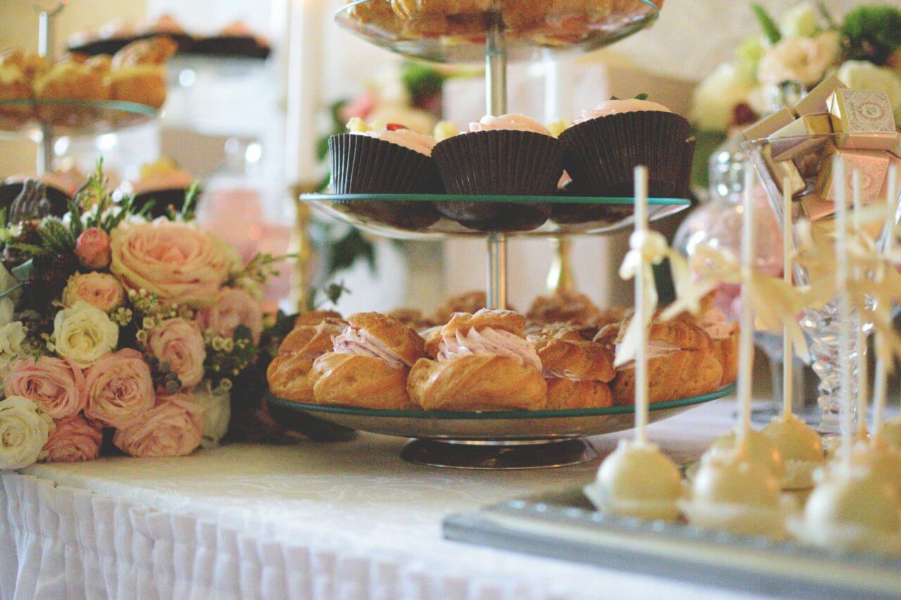 Een mooi aangeklede tafel met cupcakes, soezen en bloemen