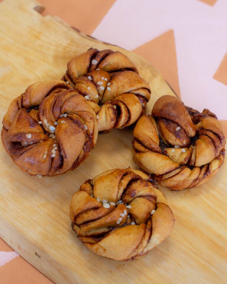 Vier vegan cinnamon buns op een serveerplank, gemaakt door Trashure Taarten, de bakker in Nijmegen.