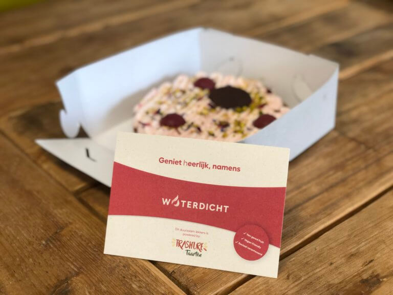 Een taart in een doos met een bedankbriefje ernaast.