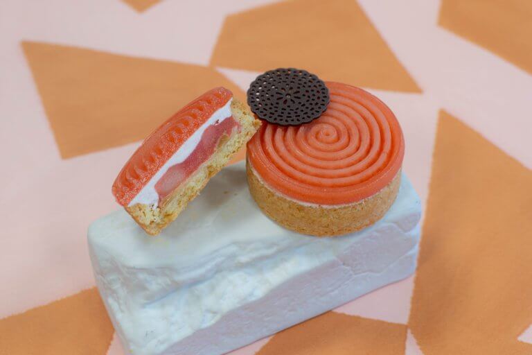 Een vegan aardbeiengebak van Trashure Taarten, de bakker in Nijmegen, geserveerd op een witte steen ter decoratie.