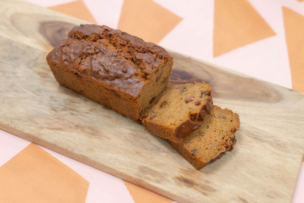 Een vegan zoete aardappel cake, geserveerd op een plank en in stukjes gesneden in onze bakkerij in Nijmegen.