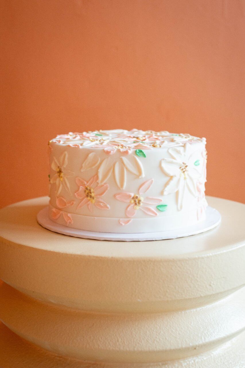 Een witte een-laags bruidstaart met kleine bloemen als versiering.