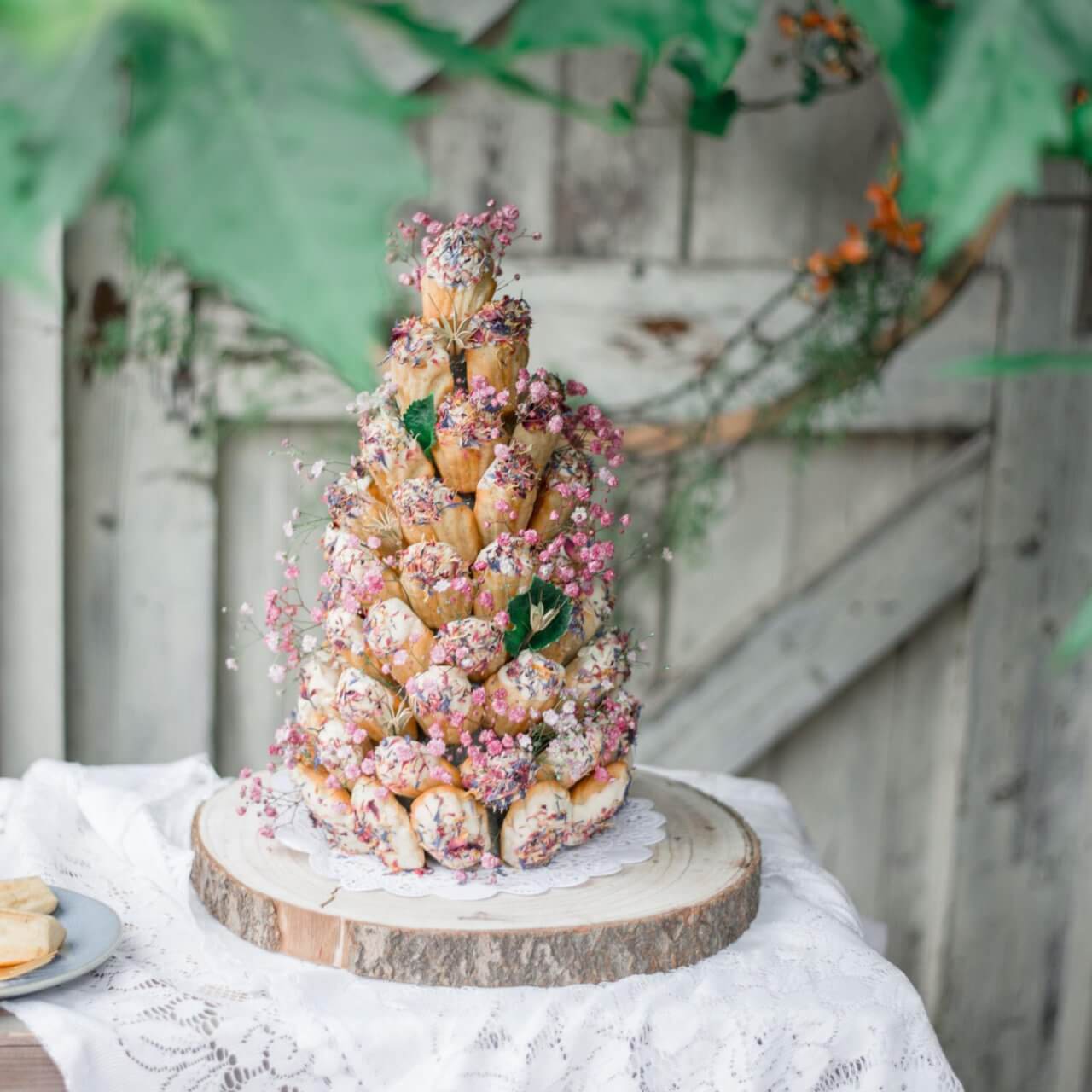 Een roze bruidstaart volledig opgebouwd uit madeleines en bloemen.