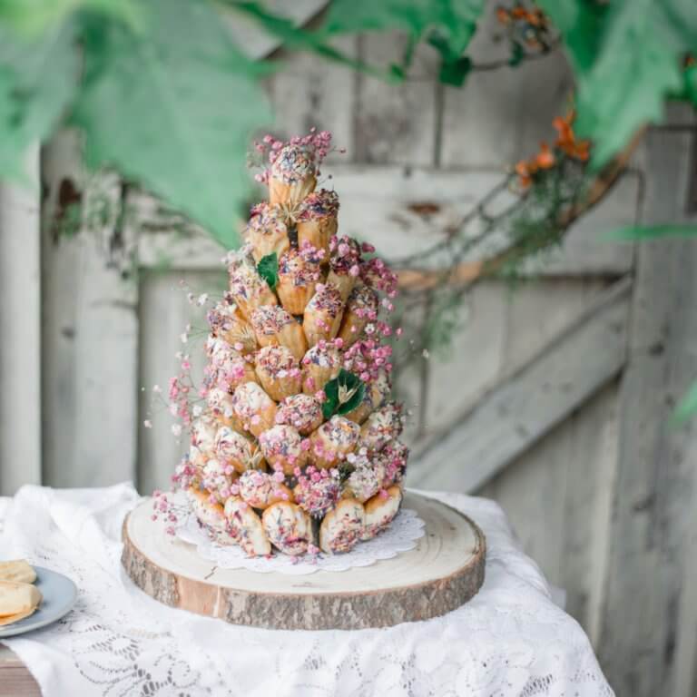 Een roze bruidstaart volledig opgebouwd uit madeleines en bloemen.