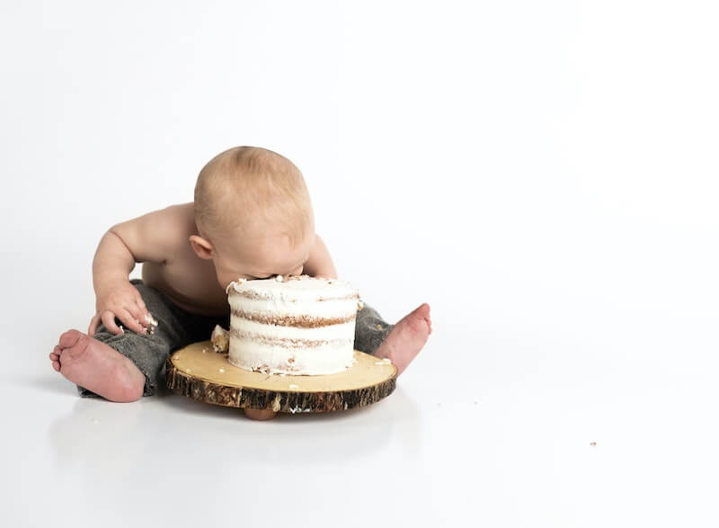 Baby neemt een hap uit een grote taart.