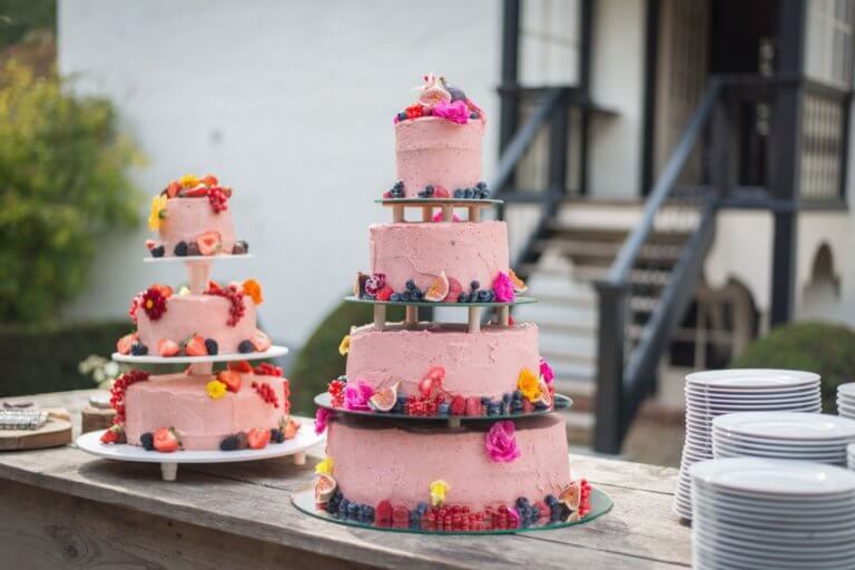 Twee mooie roze naked cakes met rood fruit en bloemen.