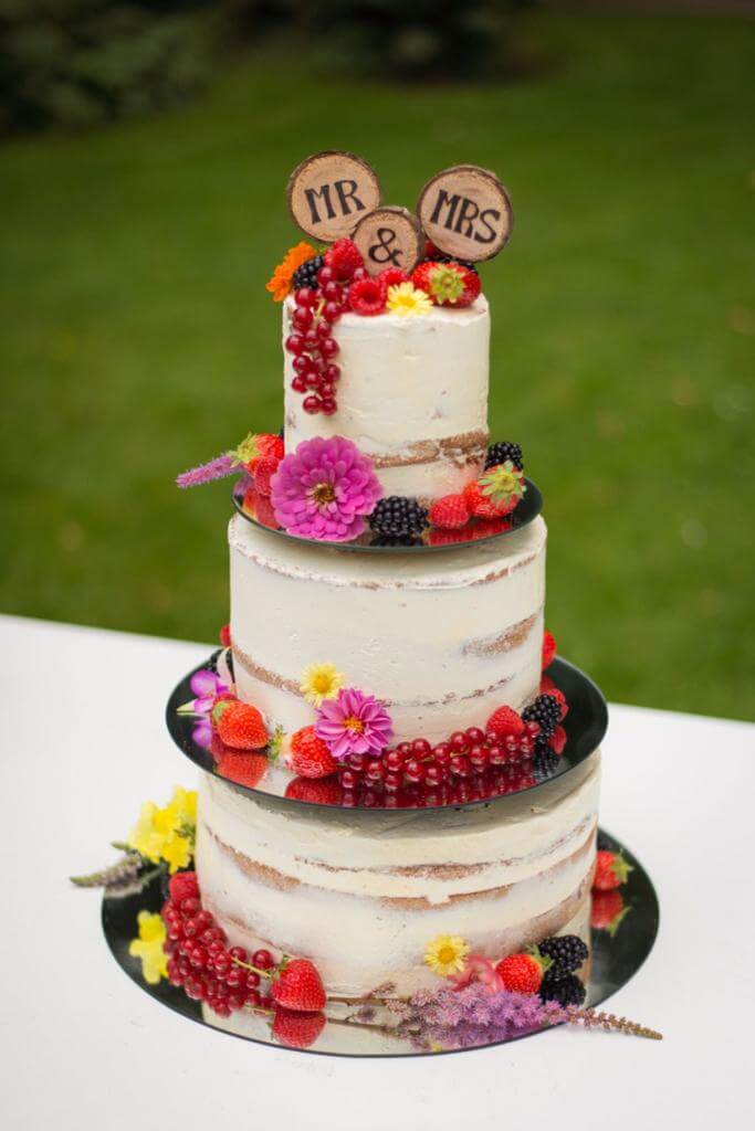 Een naked cake uit drie lagen met kleurrijke bloemen.